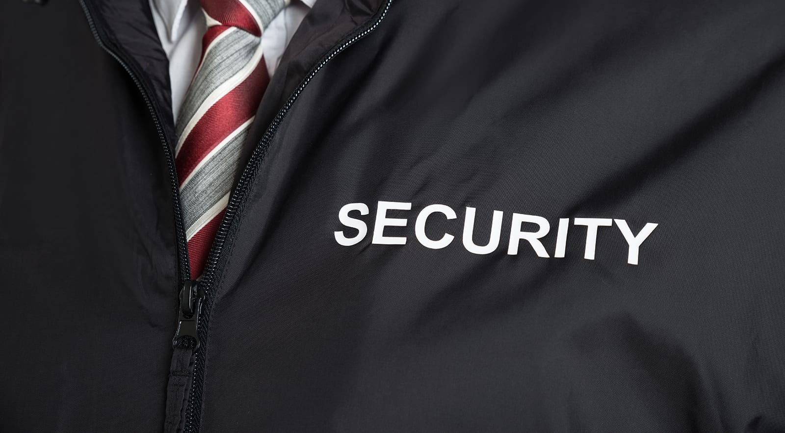 a man wearing a black jacket with the word "SECURITY" printed on it