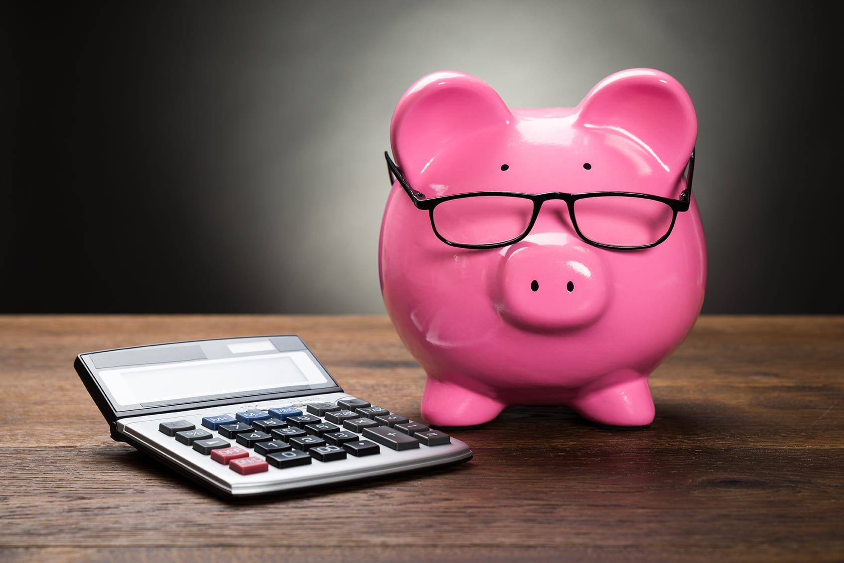 pink piggy bank next to calculator