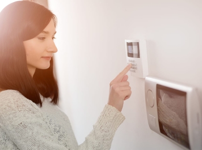 a woman adjusting a digital thermostat