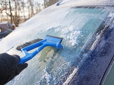 a person scrapping ice off a windshield