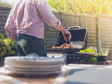 a man grilling meat in a backyard