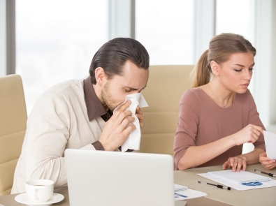 a man sneezing sitting next to his partner