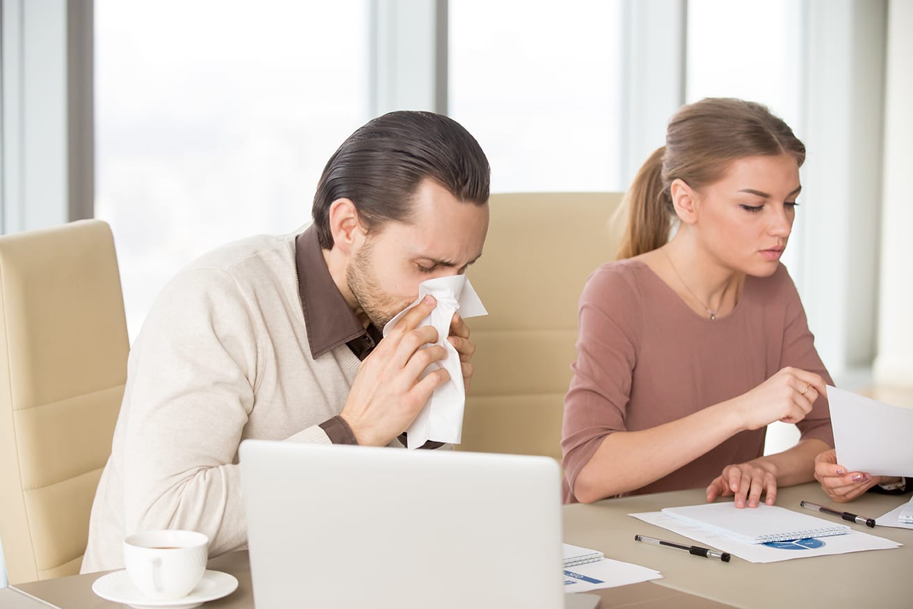 a man sneezing sitting next to his partner