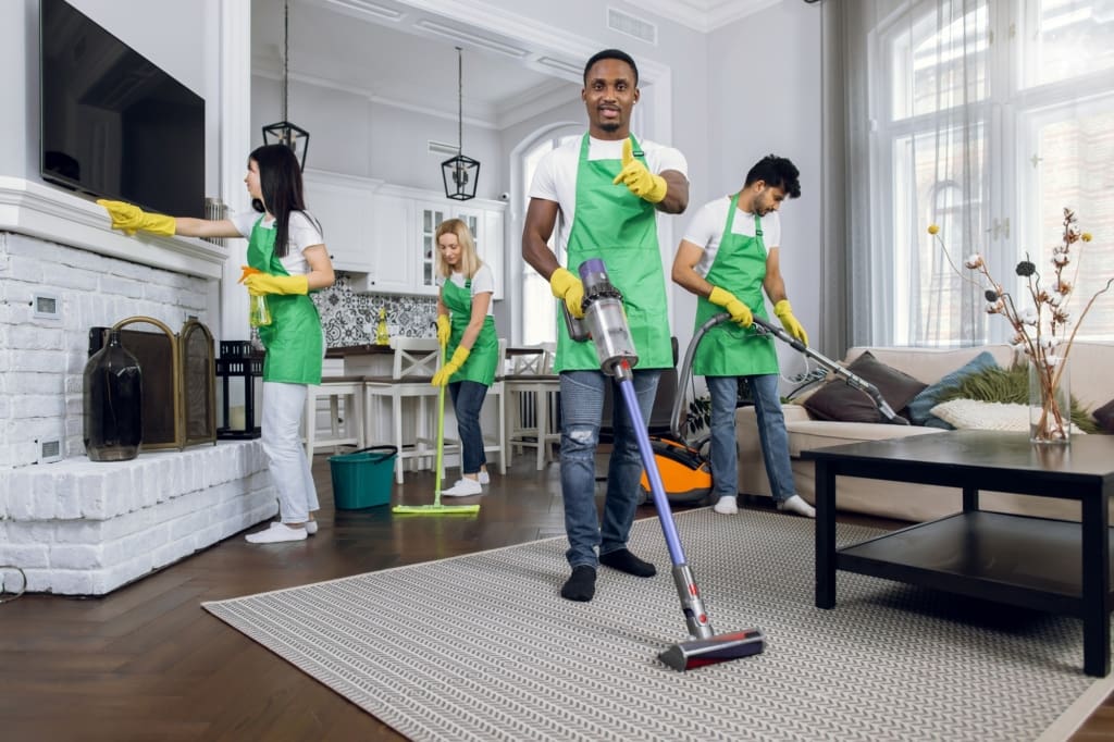 Four multicultural janitors doing cleaning at room